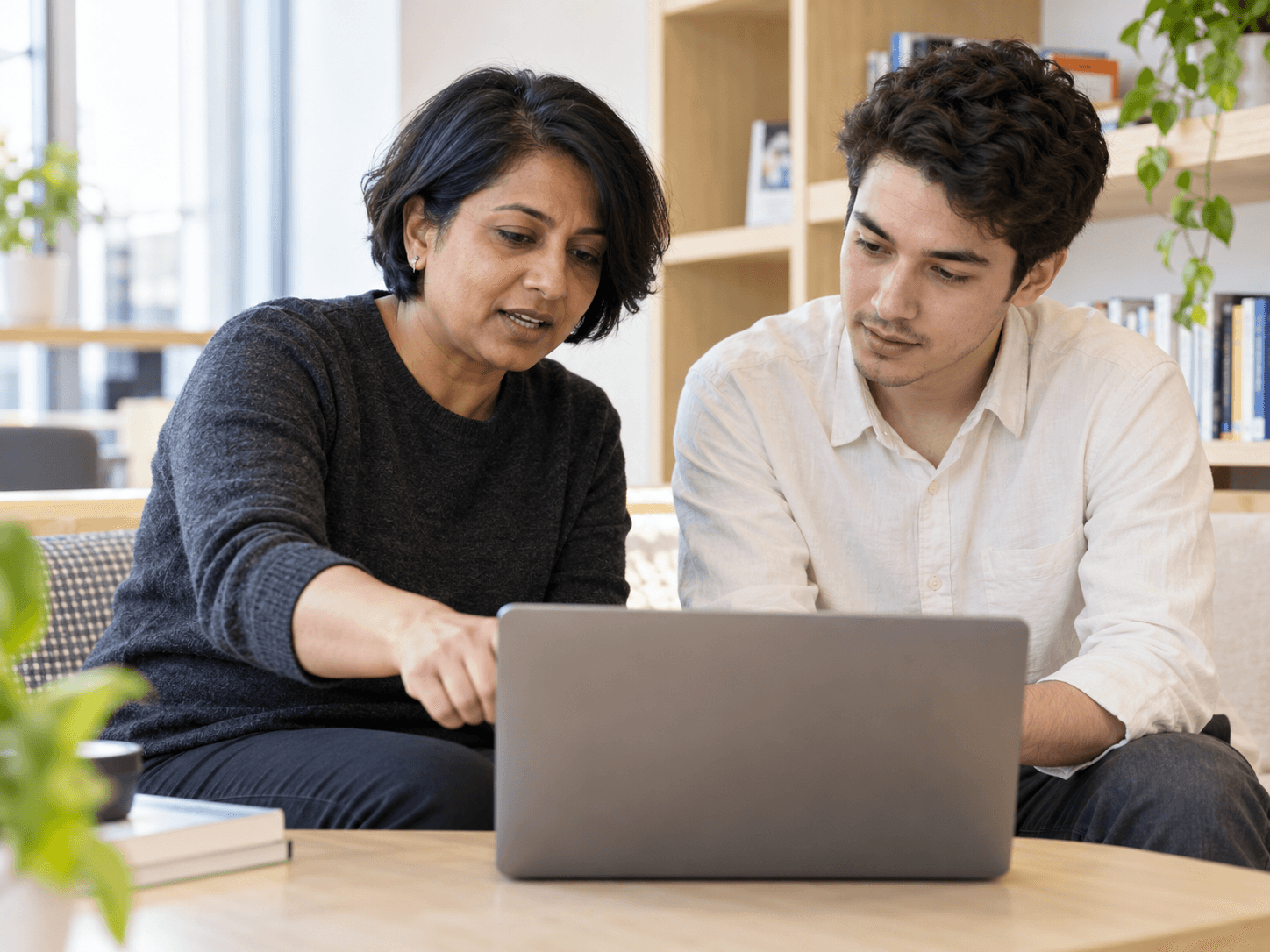 Two colleagues working through something together on a laptop